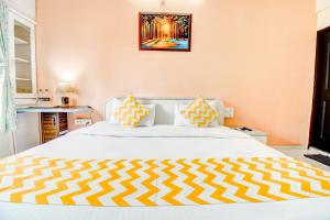 a bedroom with a large white bed with yellow and white pillows at FabHotel Corporate Residency in Pune