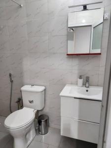a white bathroom with a toilet and a sink at F2 Appart Les Ambassades Point E, Dakar in Dakar