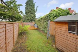 a backyard with a wooden fence and a garden at London Calling 2 bed flat 5 mins train into City. in Winchmore Hill