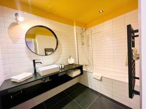 a bathroom with a sink and a mirror and a tub at Hôtel Restaurant Vaillant proche Europapark Rulantica in Sélestat