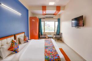een slaapkamer met een groot bed en een televisie bij FabHotel Red Roof Residency in Noida