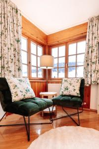 a living room with two chairs and windows at Hubertus Boutiquehotel Filzmoos in Filzmoos