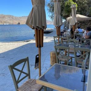 a table and chairs with an umbrella on the beach at Amalthea Luxury Suites in Symi