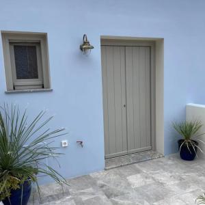 une porte dans un mur bleu avec deux plantes en pot dans l'établissement Amalthea Luxury Suites, à Symi