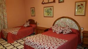 a bedroom with two beds with red and white sheets at CASA RURAL EL ESCUDERO in El Toboso