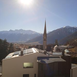 uma igreja com um campanário e um edifício com uma igreja em Apartement Noggler Zimmer mit Frühstück em Malles Venosta