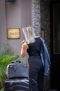 a woman is standing outside with her luggage at Hôtel Churchill Bordeaux Centre in Bordeaux