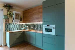 a kitchen with blue cabinets and a sink at Zielony Apartament Pod Żaglami in Zegrze Południowe