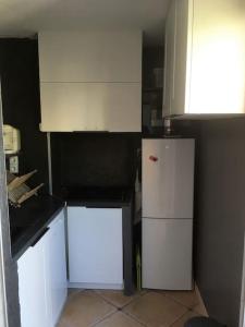 a kitchen with white cabinets and a white refrigerator at Cap Agde Studio-Cabine jardin clos, port et plage in Cap d'Agde