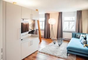 a living room with a blue couch and a tv at Boutique Hotel Friesinger in Kressbronn am Bodensee