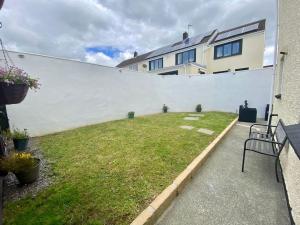 a backyard with a white wall and a grass yard at The Hoot Luxury home close to town and beaches in Pembrokeshire