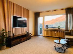 sala de estar con TV, sofá y mesa en Ferienwohnung am alten Weinberg, en Bad Berleburg