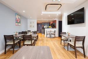 une salle à manger avec des tables, des chaises et une télévision dans l'établissement Hôtel Hoche, à Cannes