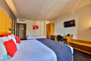 a hotel room with a large bed with red pillows at Hotel De La Couronne Liege in Liège