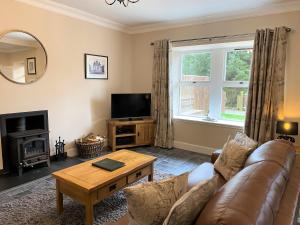 a living room with a couch and a television at Cherry Blossom Cottage in Cupar