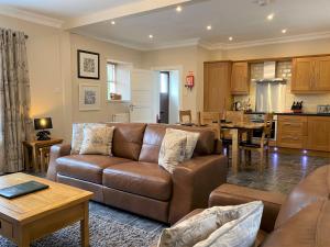 a living room with a couch and a kitchen at Cherry Blossom Cottage in Cupar