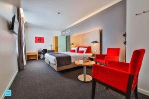 ein Hotelzimmer mit einem Bett und roten Stühlen in der Unterkunft Hotel De La Couronne Liege in Lüttich