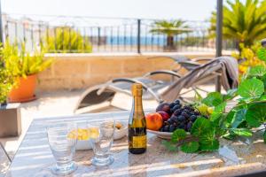 una bottiglia di vino e un cesto di frutta su un tavolo di L' ATTICO CastroSalento a Castro di Lecce