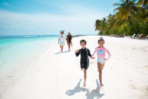 dos niños están caminando por la playa en Lily Beach Resort and Spa - All Inclusive, en Dhangethi