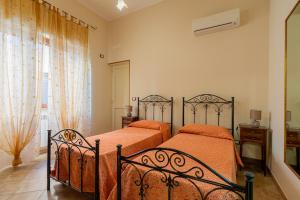 1 dormitorio con 2 camas con sábanas de color naranja y ventana en Appartamento SupersanoSalento, en Supersano