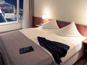 a hotel room with a large bed with a window at Mercure Hotel Riesa Dresden Elbland in Riesa