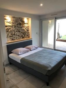 une chambre avec un lit avec un mur en pierre dans l'établissement Les Palmiers. Charme, spa et massage en vignoble nantais, au Pallet