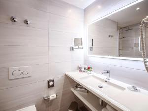 Baño blanco con lavabo y espejo en Mercure Hotel Riesa Dresden Elbland, en Riesa