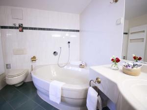 a white bathroom with a tub and a toilet at Mercure Hotel Riesa Dresden Elbland in Riesa