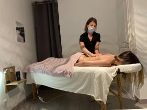 une femme en masque assise sur un lit d'hôpital dans l'établissement Les Palmiers. Charme, spa et massage en vignoble nantais, au Pallet