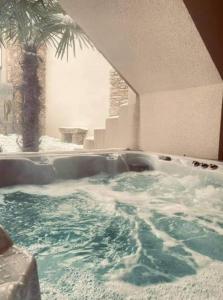 une baignoire jacuzzi dans une chambre avec un palmier dans l'établissement Les Palmiers. Charme, spa et massage en vignoble nantais, au Pallet