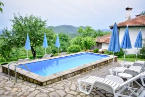 a swimming pool with chairs and umbrellas at Дядо Петковата Къща in Elena