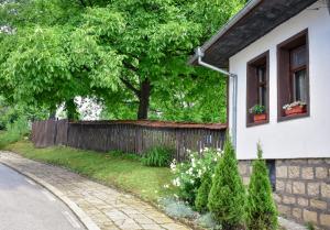 a house with a fence and a tree in a yard at Дядо Петковата Къща in Elena