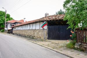 a building with a flag on the side of it next to a street at Дядо Петковата Къща in Elena