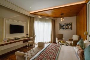 a hotel room with a large bed and a television at Regenta Place Mohali in Mohali