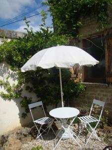 ein weißer Tisch, zwei Stühle und ein Regenschirm in der Unterkunft La maison d'Agnes en Haute Bourgogne in Jully