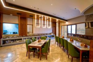 a restaurant with wooden tables and green chairs at Regenta Place Chandigarh Mohali in Mohali