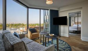 a living room with a couch and a large window at Pendry Washington DC - The Wharf in Washington