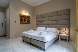 una camera da letto con un letto grande con una grande testiera di Correnti Boutique Hotel Gold a Sanremo Altre 9 foto