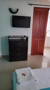 a bedroom with a dresser with a television and a door at Casa Evelyn in Cartagena de Indias