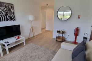 a living room with a couch and a tv and a mirror at Apartamento Praia-Mar in Ponta Delgada