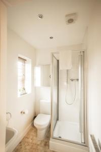 a white bathroom with a toilet and a shower at Upton Grange Townhouse in Chester