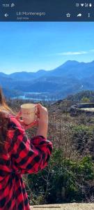 Eine Frau, die eine Tasse Kaffee auf einem Berg hält. in der Unterkunft Skadar Lake Family Resort in Rijeka Crnojevića