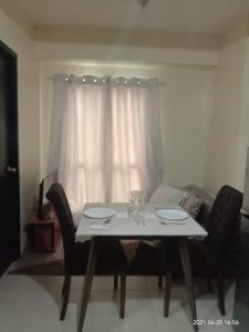 a dining room table with two chairs and a white curtain at The Rochester Condo in Manila