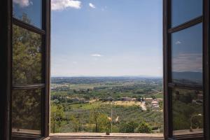 una ventana con vistas a un campo visto a través de ella en Casa Livia - Stately house with elevator en Lucignano