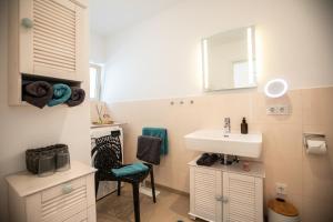 baño con lavabo, espejo y silla en Claudia's Seeherz, en Wasserburg