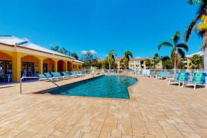basen z niebieskimi krzesłami i budynek w obiekcie Beach Sunflower, Unit #516 w mieście Fort Myers