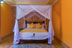 a bedroom with a canopy bed with yellow pillows at Nokras Riverine Hotel & Spa in Sagana