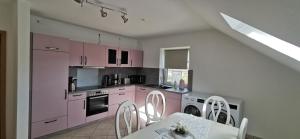 a kitchen with pink cabinets and a table and chairs at Ferienwohnung Sternenkieker in Krummhörn