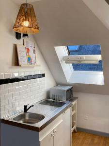 Elle comprend une petite cuisine avec un évier et une fenêtre. dans l'établissement Studio un cocon à la campagne, à Saint-Samson-sur-Rance