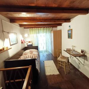 a bedroom with a bed and a desk and a window at La casetta delle bambole. in Massello